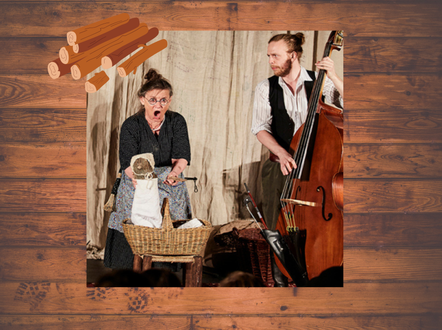 En kvinde står med et stykke brænde med tøj på. En mand står ved siden af med en kontrabas. 